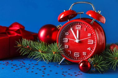 Kırmızı Yeni Yıl saati ve mavi arkaplanda köknar dalları