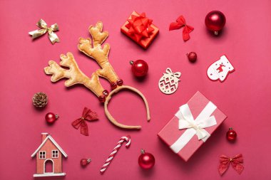 Kırmızı arka planda hediye ve dekorla Noel geyiği boynuzları
