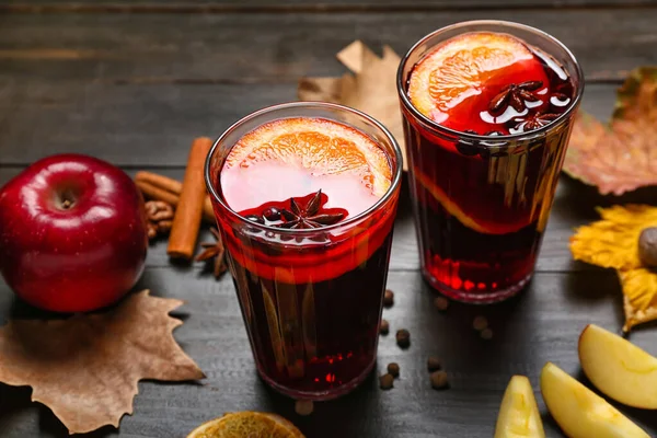 Glasses of aromatic mulled wine on dark wooden background