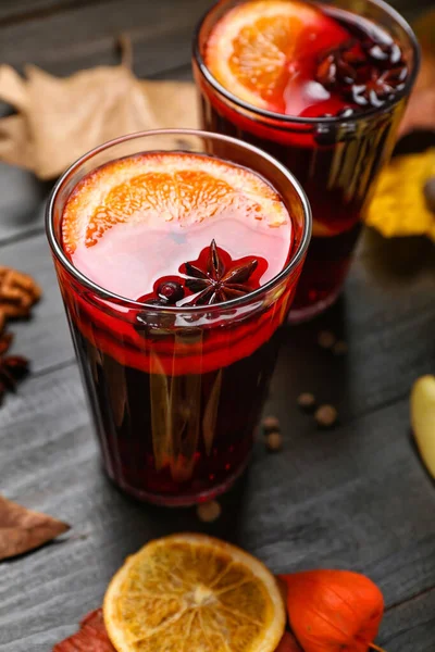 Glasses of aromatic mulled wine on dark wooden background, closeup