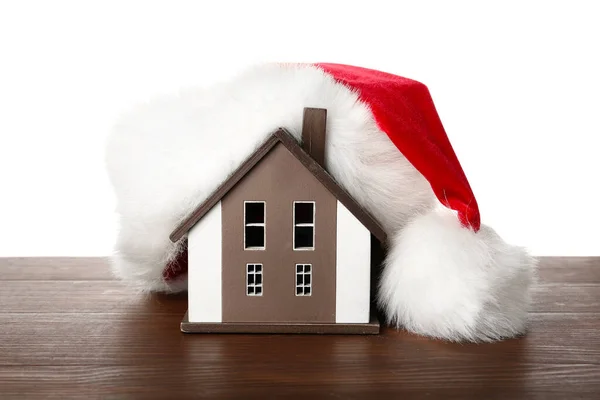 stock image House model with Santa hat on table against white background