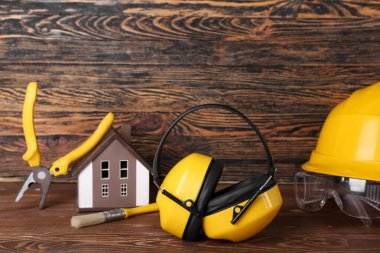 Koyu ahşap arka planda inşaat aletleri olan işitme koruyucular