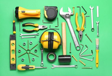 Yeşil arka planda inşaatçı araçları olan işitme koruyucular