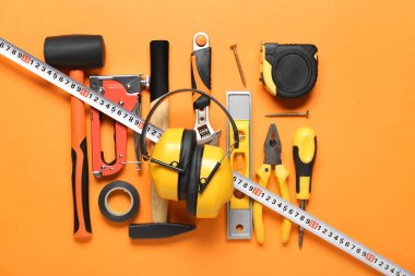 Renk arkaplanı üzerinde inşa araçları olan işitme koruyucuları