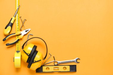 Renk arkaplanında işitme koruyucuları olan inşaatçının araçlarından yapılmış çerçeve