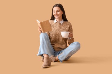 Bej arka planda bir fincan kakao okuyan güzel bir kadın.