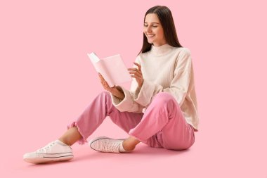 Güzel bir kadın pembe arka planda kitap okuyor.