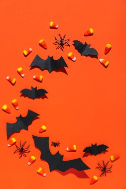 Kırmızı arka planda kağıt yarasalardan, örümceklerden ve mısır şekerlerinden yapılmış çerçeve