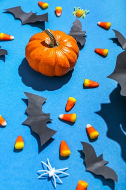 Cadılar Bayramı balkabaklı kağıt yarasalar ve mavi arka planda mısır şekeri