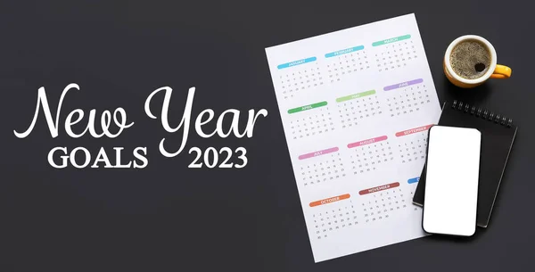 Paper sheet with calendar, mobile phone, notebook and cup of coffee on black background. Concept of new year goals