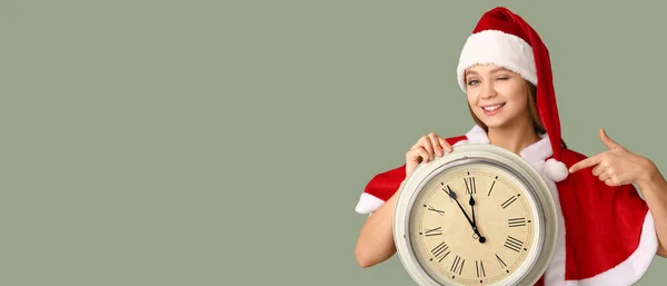 穿着圣诞老人服装的年轻漂亮的女人拿着彩色背景的钟 上面有文字的空间 圣诞倒计时概念 — 图库照片