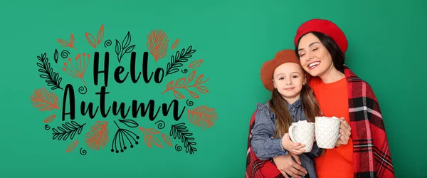 女人和她的小女儿带着美味的热巧克力和绿色背景的短信Hello Autumn — 图库照片
