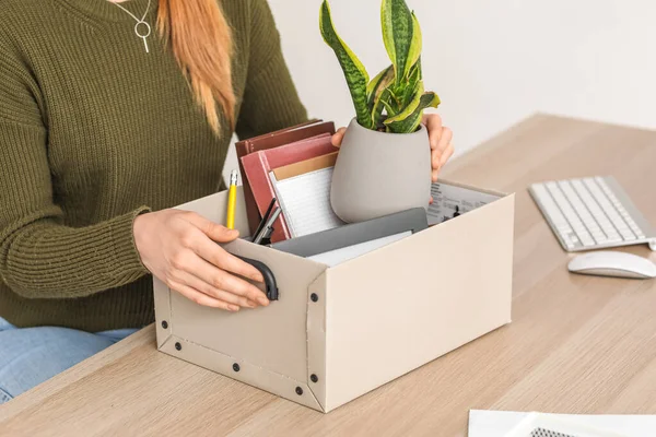 Fired young woman with packed stuff sitting at table in office, closeup