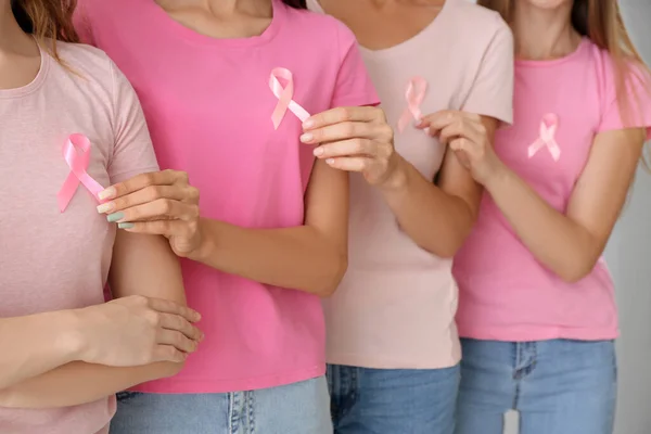 光の背景にピンクの意識のリボンを持つ女性 クローズアップ 乳がんの概念 — ストック写真