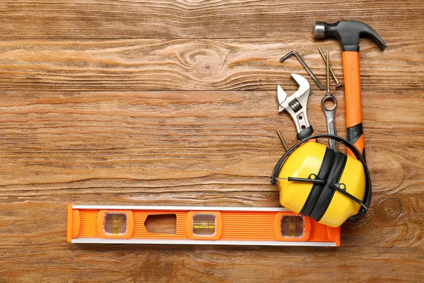 Frame made of builder's tools with hearing protectors on wooden background