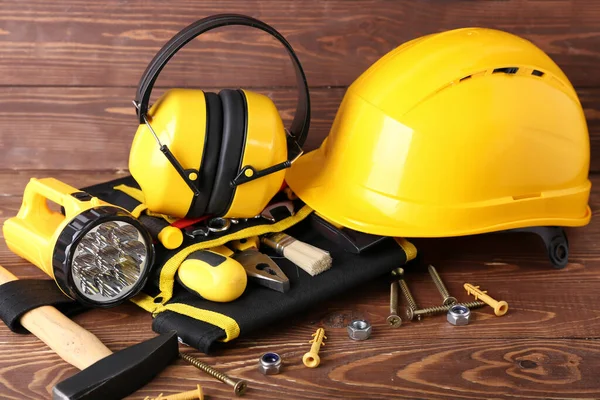 Hearing protectors with builder's tools on dark wooden background