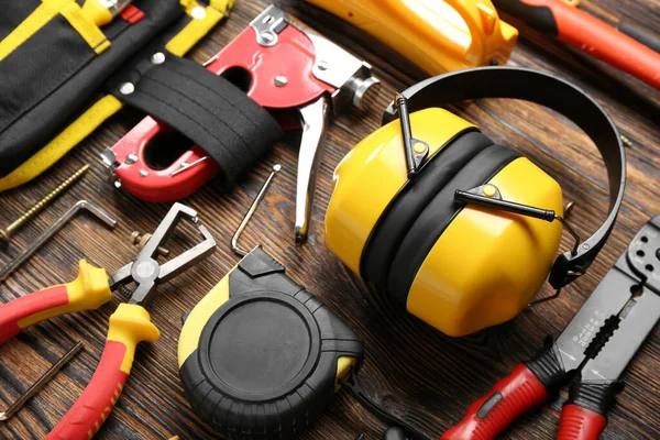 Hearing protectors with builder's tools on dark wooden background