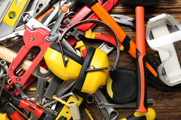 Hearing protectors with builder's tools on dark wooden background