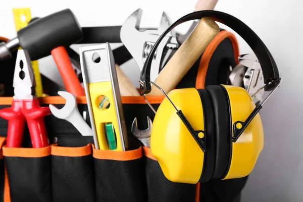 Bag with builder's tools and hearing protectors on light background