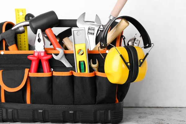 Bag with builder's tools and hearing protectors on light background