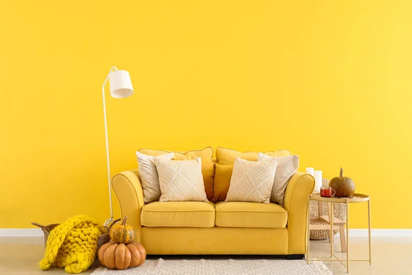 Interior of bright living room with yellow sofa and pumpkins