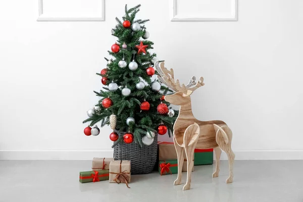木のトナカイとクリスマスツリーと光の壁の近くのプレゼント — ストック写真