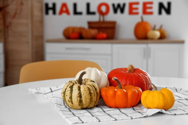 Halloween pumpkins on dining table in light kitchen, closeup