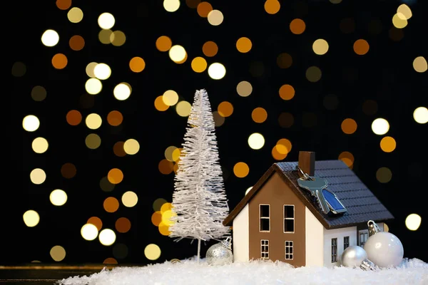 鍵付きの家のモデル ぼやけた光に対するテーブルの上のクリスマスの装飾と雪 — ストック写真