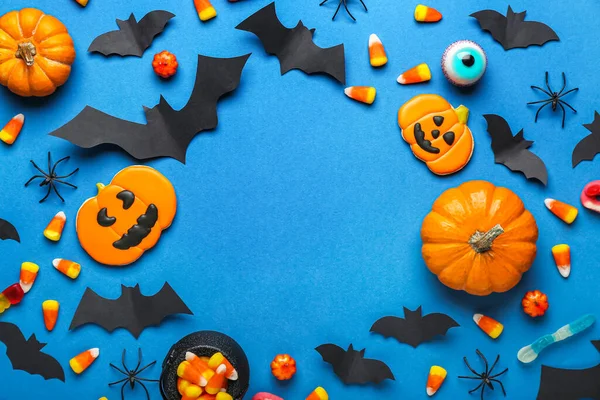 ハロウィンのお菓子で作られたフレーム 青い背景に紙のコウモリとクモ — ストック写真