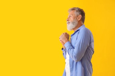 Sarı arka planda düşünceli olgun bir adam.