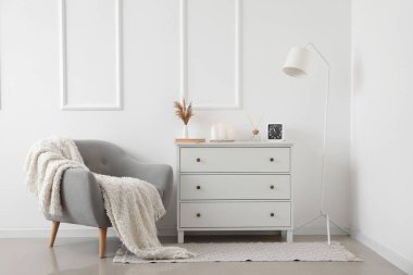 Gri koltuklu, çekmeceli ve lambalı, aydınlık oturma odasının içi.