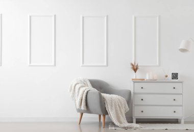 Gri koltuklu, çekmeceli ve lambalı, aydınlık oturma odasının içi.