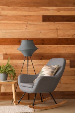 Gri koltuğu, masası ve lambası olan rahat oturma odasının içinde.