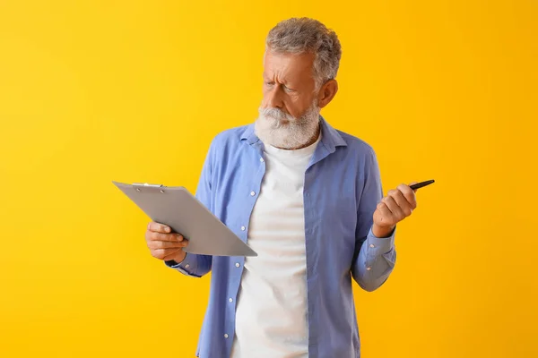 Thoughtful Mature Man Pen Clipboard Yellow Background — Stock Photo, Image
