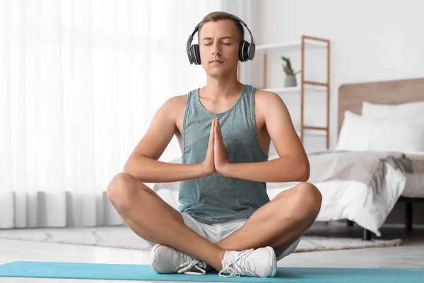 Hombre Joven Con Auriculares Meditando Alfombra Dormitorio — Foto de Stock