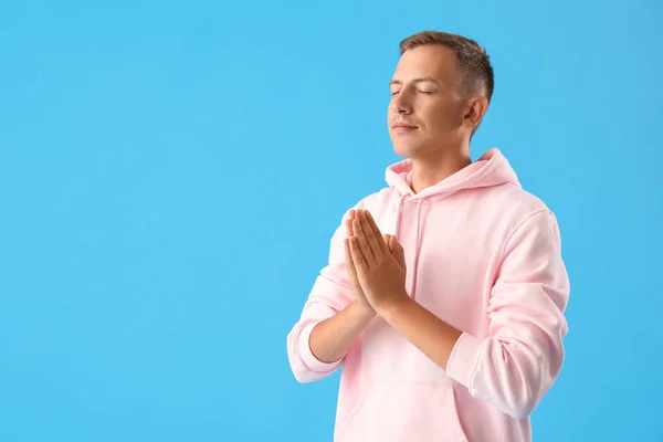 若いです男でピンクパーカー瞑想上の青の背景 — ストック写真