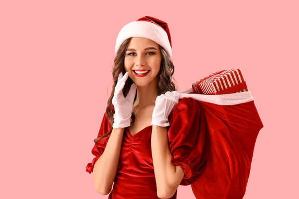 戴着圣诞礼帽的漂亮女人提着粉色背景的礼品袋 — 图库照片