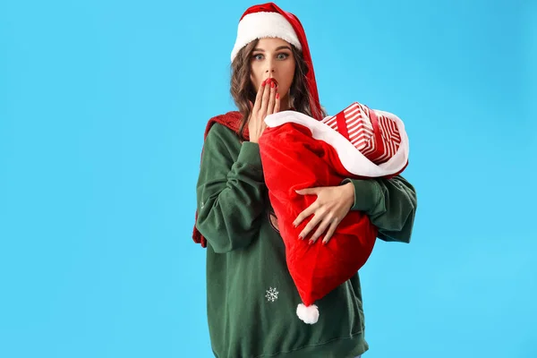 Mavi Arka Planda Hediyeler Taşıyan Noel Baba Şapkalı Genç Kadın — Stok fotoğraf