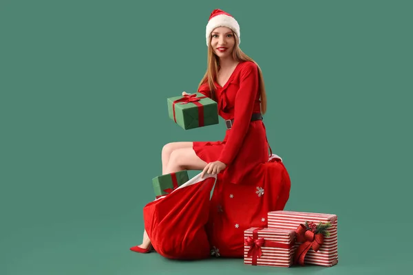 Beautiful Young Woman Santa Hat Bag Gifts Sitting Green Background — Stock Photo, Image