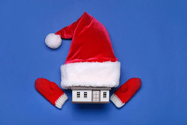 House model with Santa hat and mittens on blue background