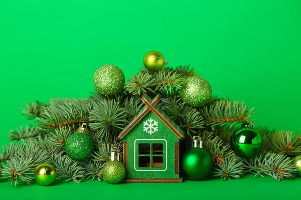 緑の背景にクリスマスボールとモミの枝と家の図 — ストック写真