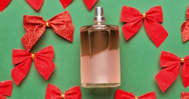 Bir şişe parfüm ve yeşil arka planda Noel yayları.