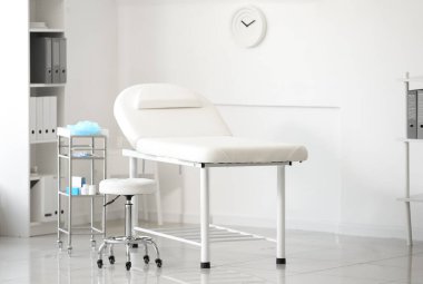 Doktor malzemeleriyle dolu kanepesi ve masası olan modern tıp bürosu.