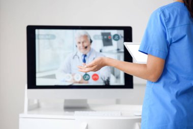 Hemşire klinikte doktorla görüntülü konuşma yapıyor.