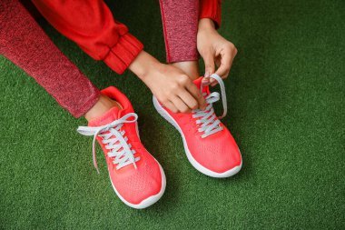 Yeşil arka planda ayakkabı bağlayan kadın, yakın plan.