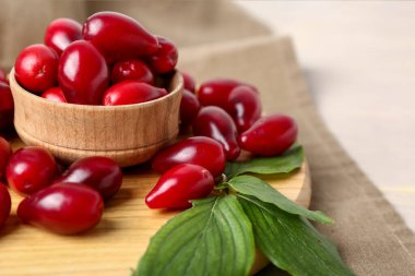 Tahta ahşap tahta ve olgun kırmızı kızılcık meyveleri ile kase ve masa üzerinde yapraklar, yakın çekim