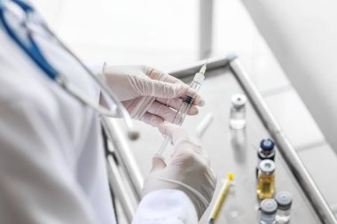 Klinikteki masanın yanında şırıngalı kadın doktor, yakın plan.