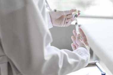 Klinikte şırıngası ve ampülü olan kadın doktor, yakın plan.
