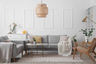 Gri koltukları, masası ve koltuğu olan aydınlık oturma odasının içinde.