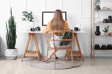 Işık ofisinde bilgisayarla çalışan kadın fotoğrafçı.